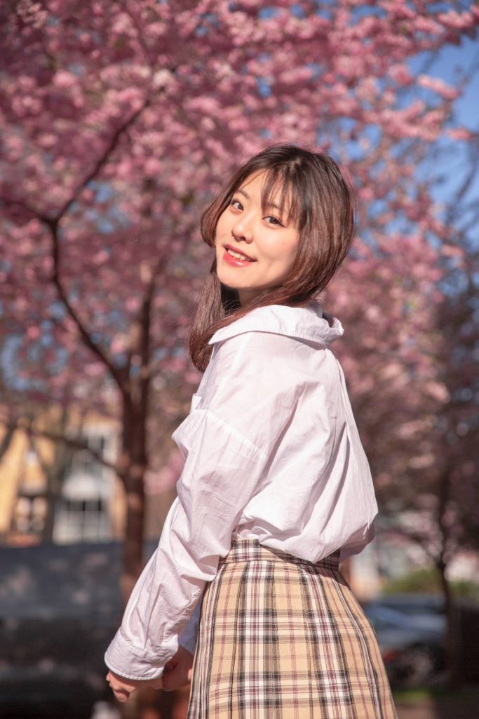 woman looking at the camera with cute pose and cherry blossom on the background